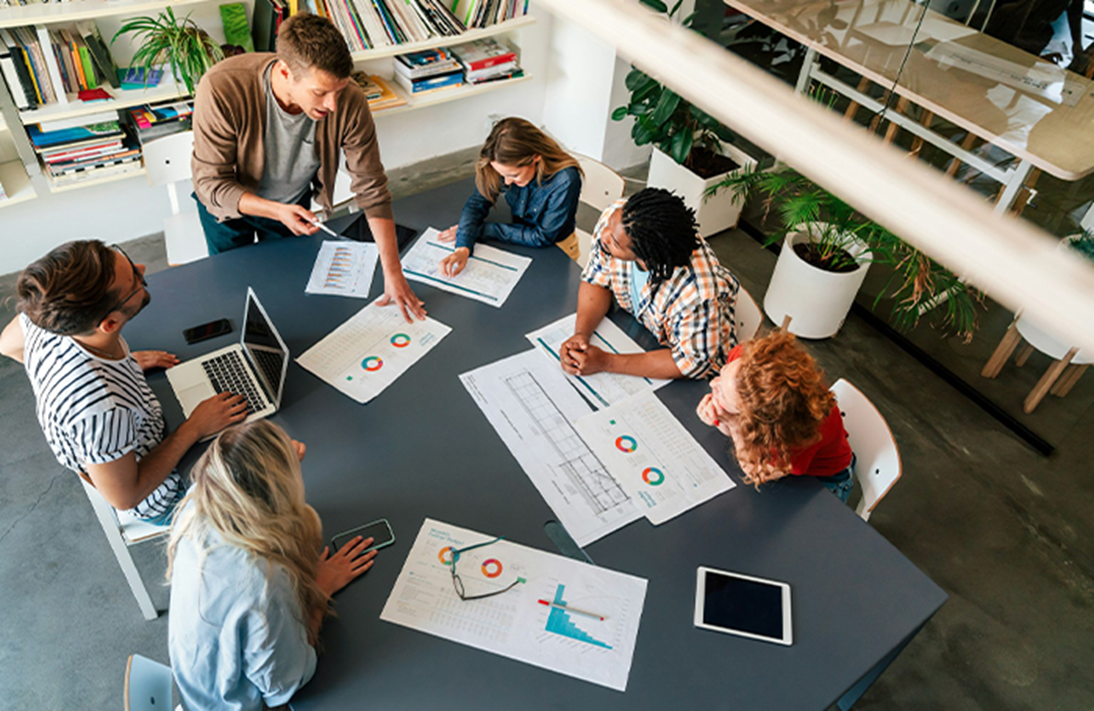 Team of diverse professionals in a modern office collaborating on business charts and reports during a meeting
