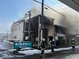 Firefighters responding to a building fire with heavy smoke coming from a two-story structure on a snowy street
