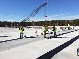 Commercial roofing contractors applying waterproof membrane or sealant on a large construction site. Industrial flat roof installation