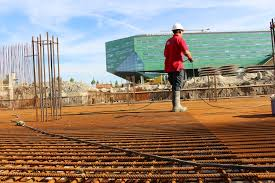 Steel reinforcement installation on a commercial construction site. Worker inspecting rebar deck prior to foundation concrete pouring